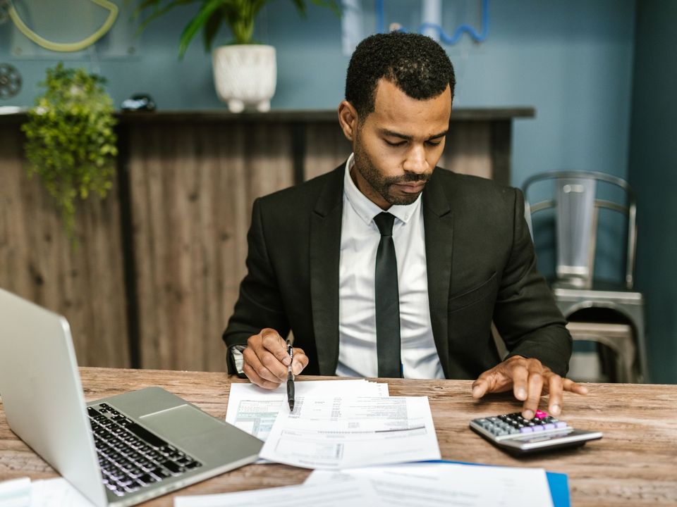 An accountant in a suit checking figures with a calculator
