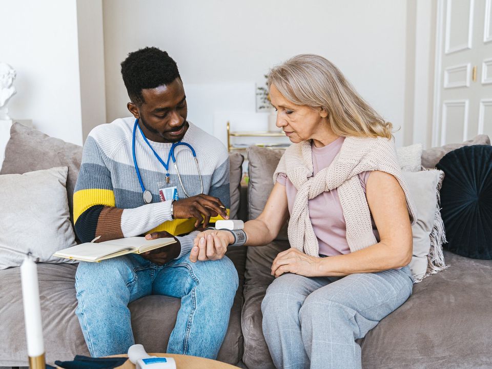 An aged-care worker sitting with an elderly resident