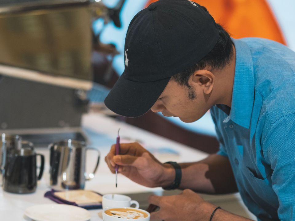 A young man making coffee behind a cafe counter