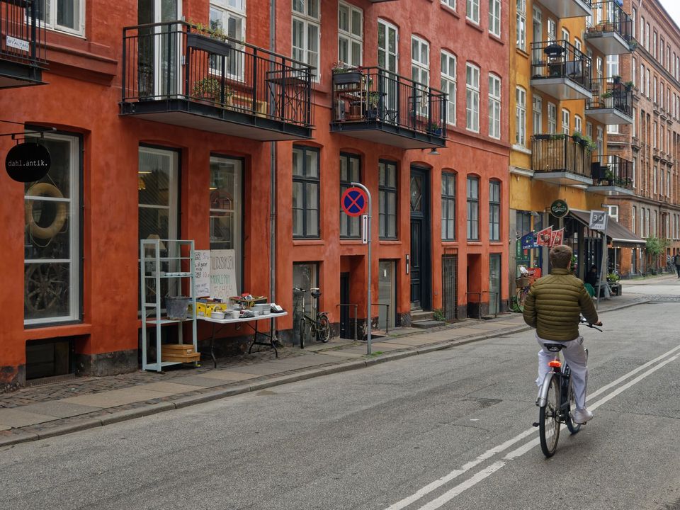 A cyclist riding down a Copenhagen street lined with brick buildings