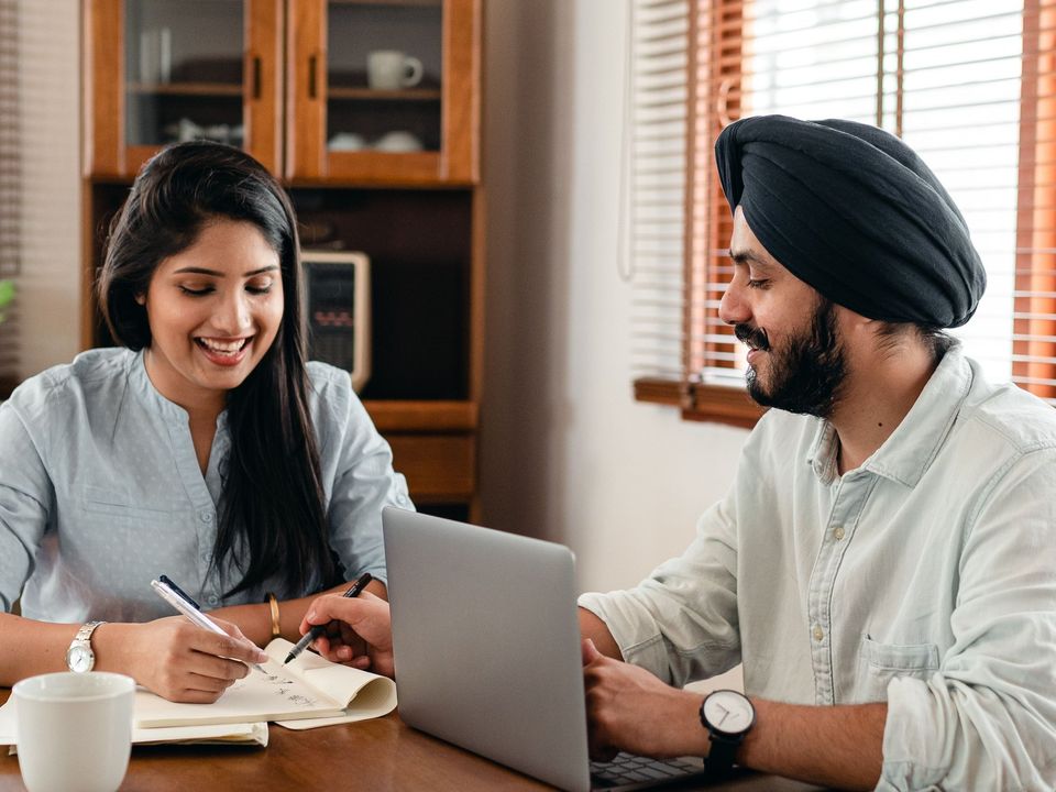 A smiling counsellor taking notes while a student talks through his plans at an office desk