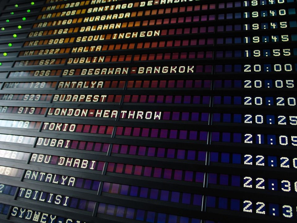 An airport departures board listing London Heathrow and Sydney flights