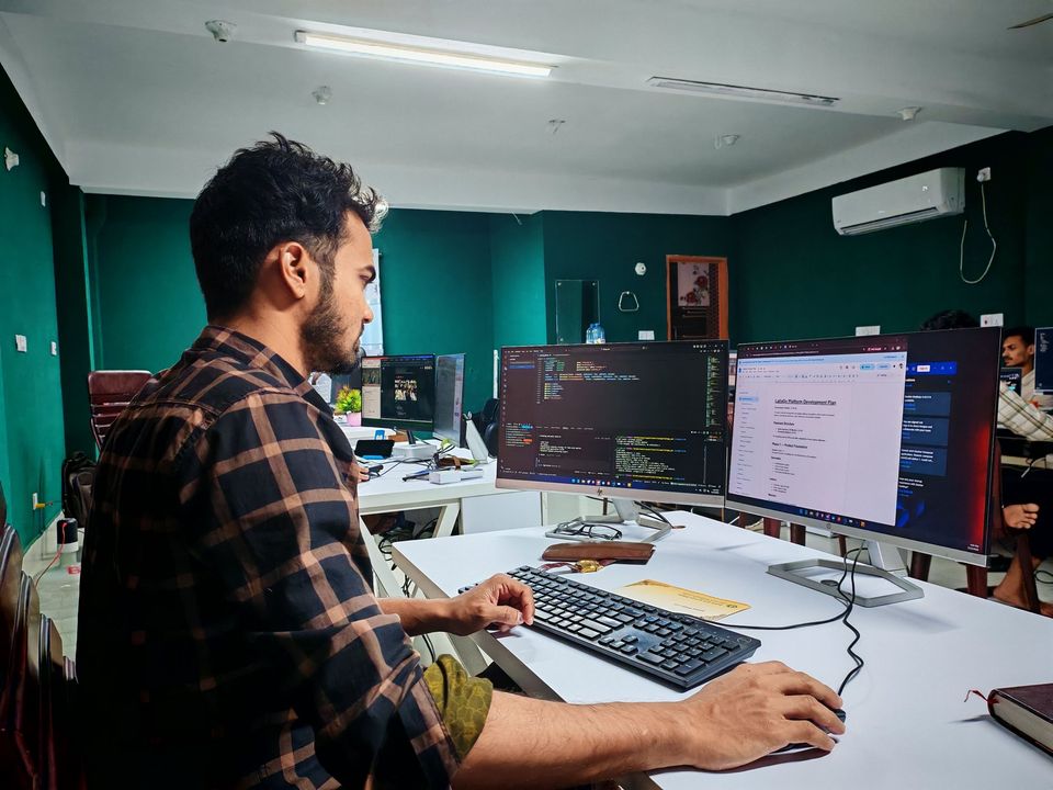 A developer writing code across two monitors in an office