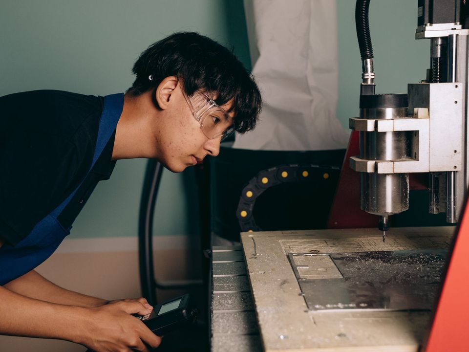 Young engineer operating a CNC machine in a workshop.