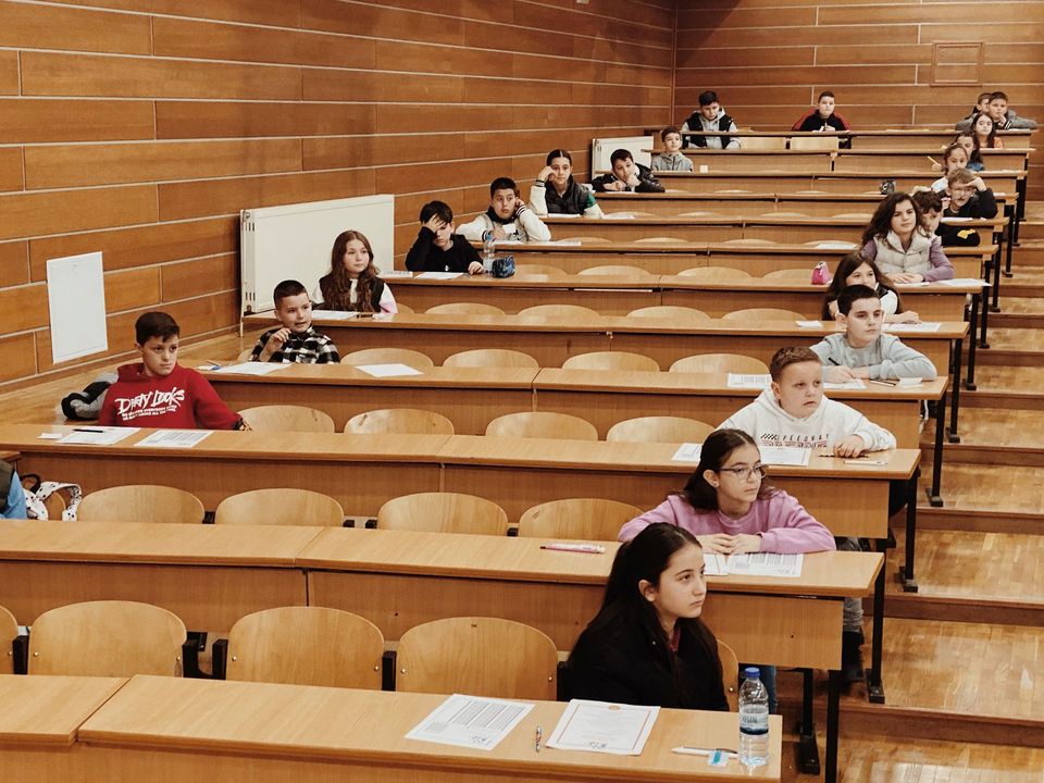 Students writing at rows of desks in an exam hall