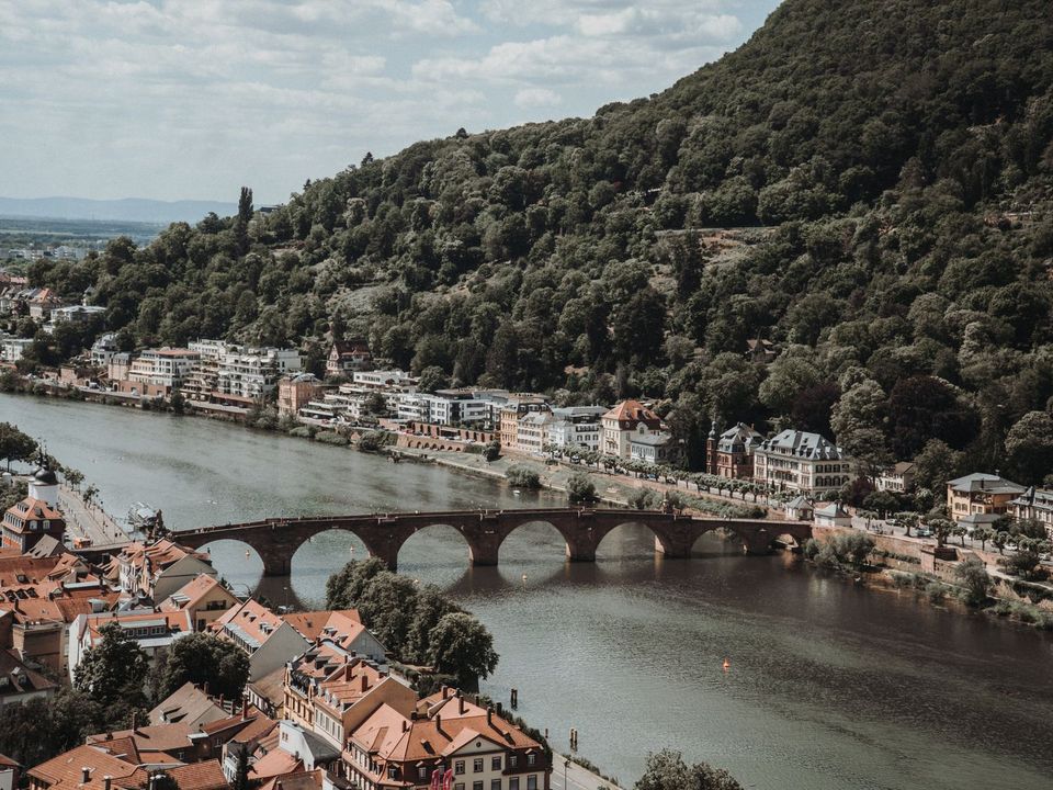 Heidelberg's old bridge and the Neckar River below a forested hill