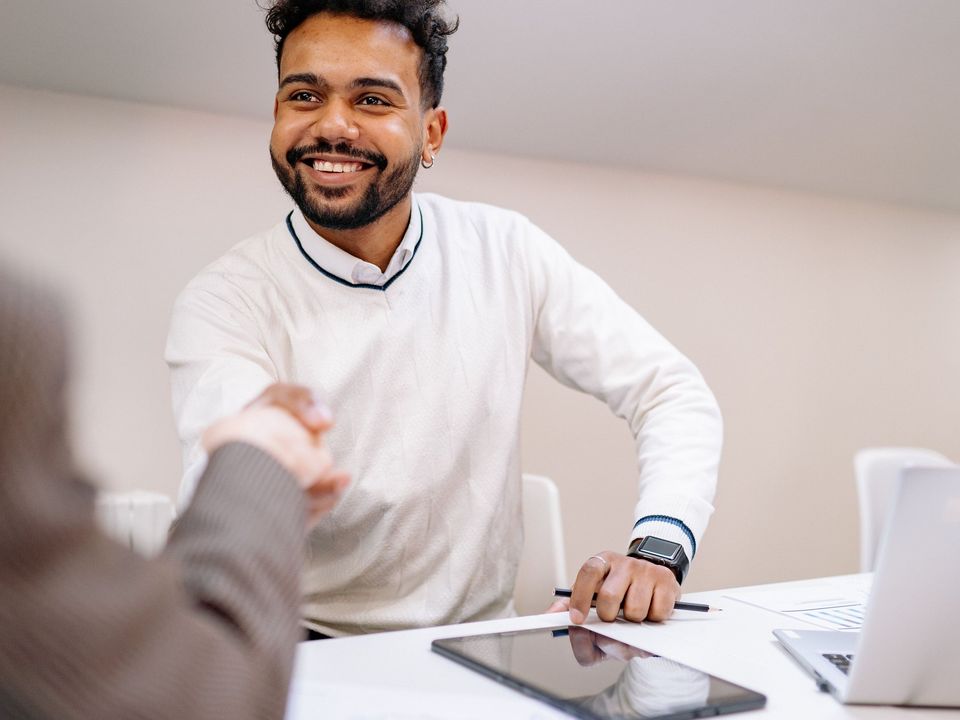 A smiling young man shaking hands at a job interview