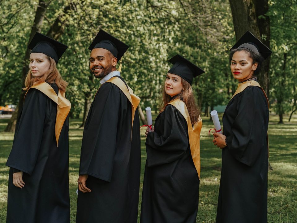 Graduates in caps and gowns standing together in a park