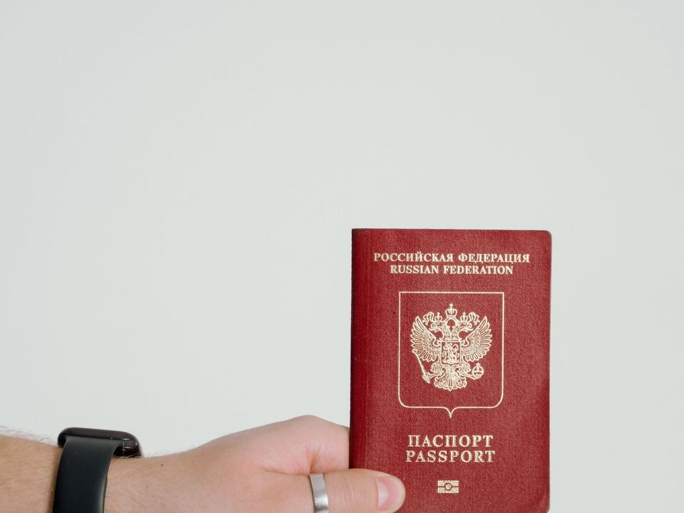 A hand holding up a red passport
