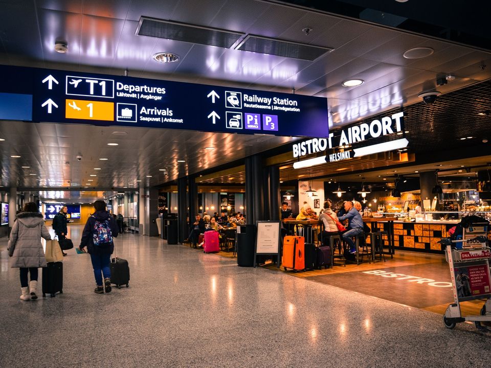 Travellers with luggage in Helsinki Airport's arrivals hall