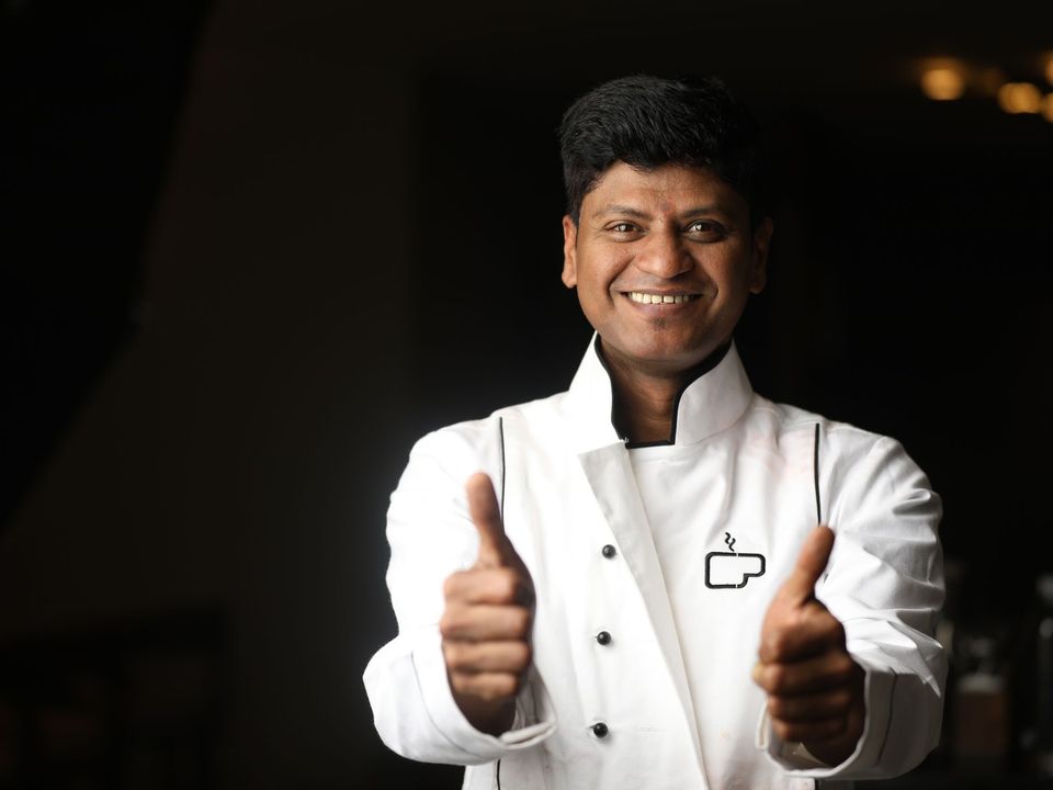 A cheerful chef in a white uniform giving a thumbs up.
