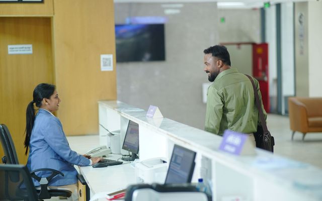 A hotel front-desk trainee helping a guest at reception