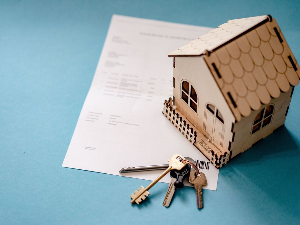 A model house, keys and property papers on a table