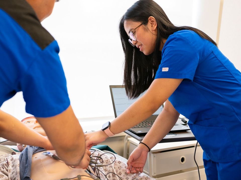 Nursing students practise on a medical mannequin in a simulation lab