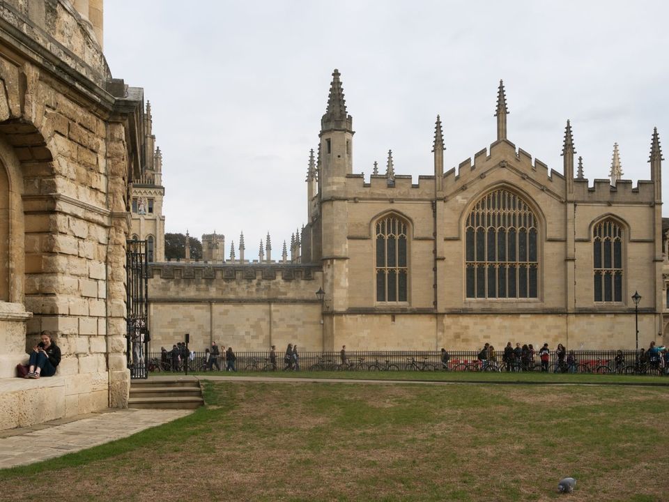 Students relaxing outside a historic college building in Oxford, England
