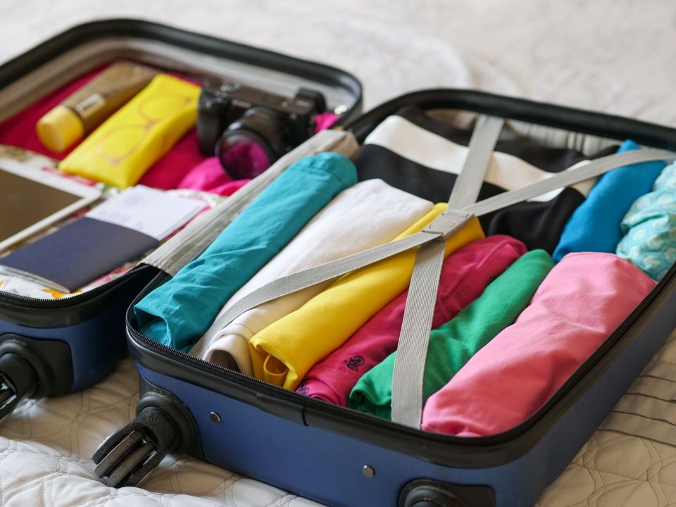 An open suitcase packed with folded clothes