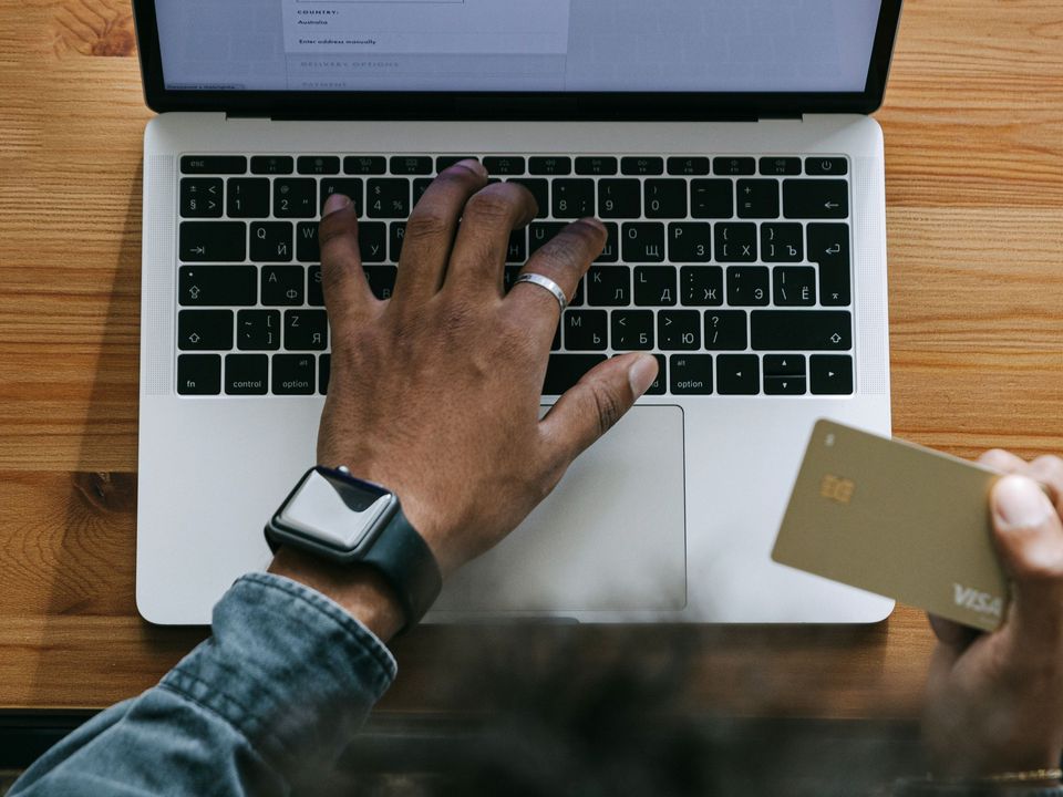 Hands typing on a laptop with a bank card beside it