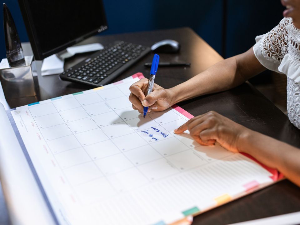 A hand writing dates into a large planner