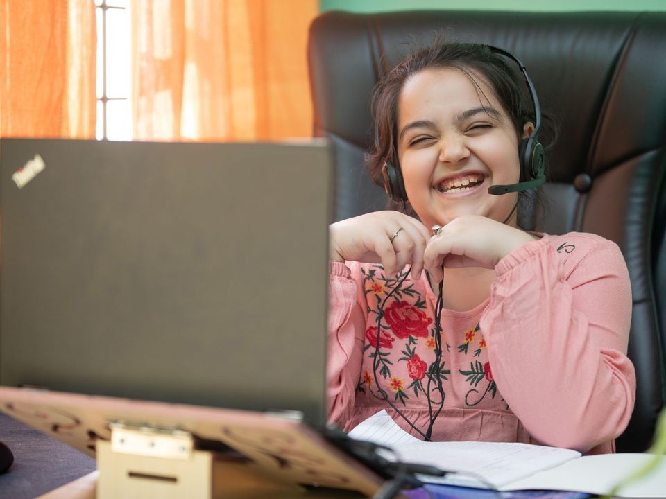 Smiling young woman with a headset on a video call, studying online.