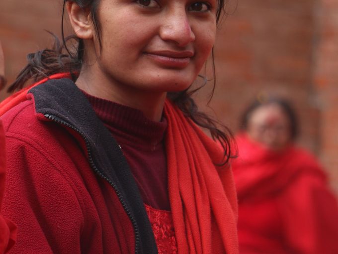 A smiling young woman in a red top, outdoors