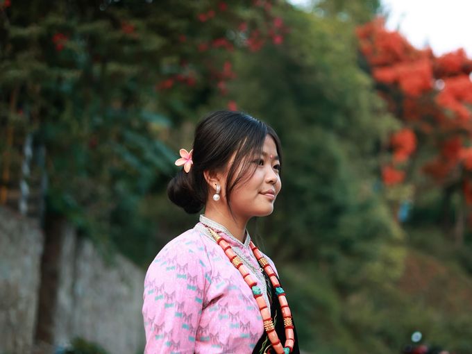 A young woman in a pink kurta standing outdoors under trees