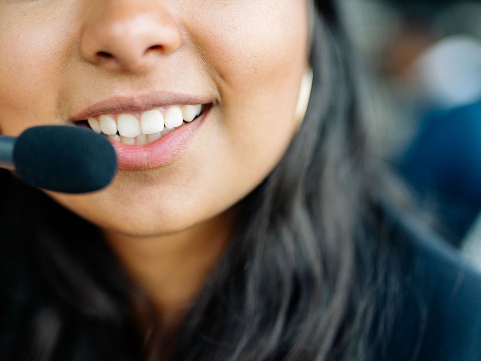 A smiling young woman speaking into a headset microphone