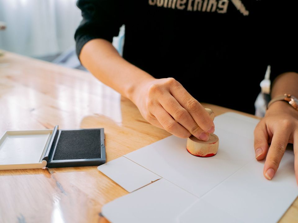 A hand pressing an official stamp onto a document