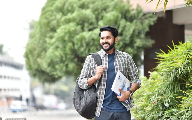 A student with a backpack and books walking outdoors