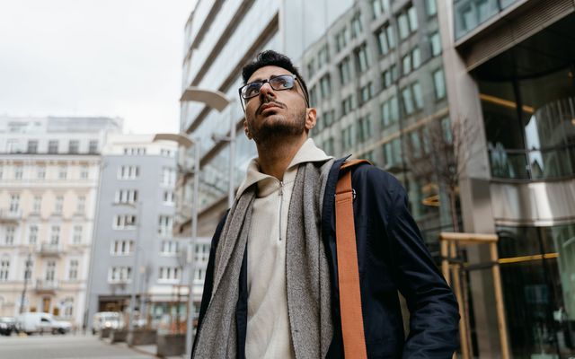 A student with a shoulder bag among modern city buildings