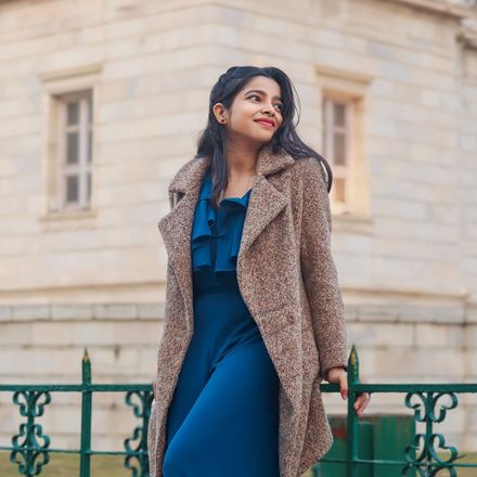 A student in a winter coat outside an old European building