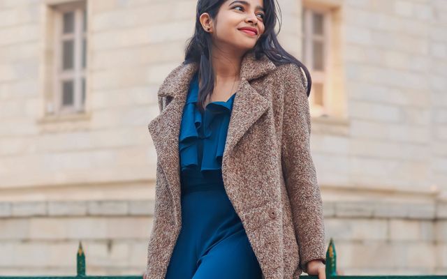 A student in a winter coat outside an old European building