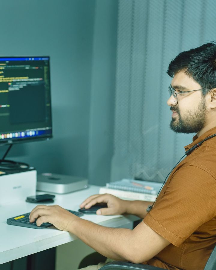 A student writing code on two monitors