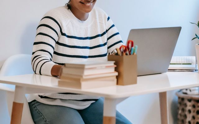 A business student smiling at her laptop at a small desk