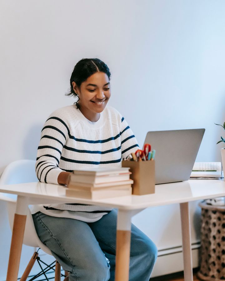 A business student smiling at her laptop at a small desk