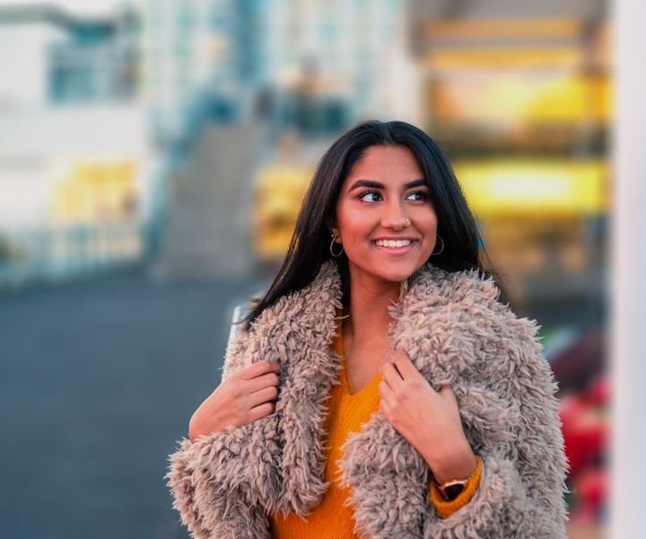 A smiling student in a winter coat on a city street