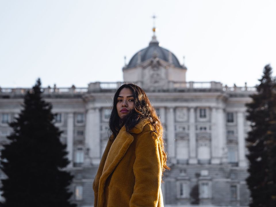A student in a yellow coat in front of a European palace in winter