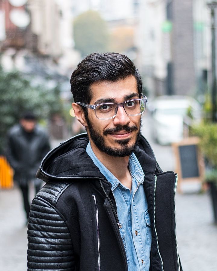 A smiling student in a black jacket on a European street