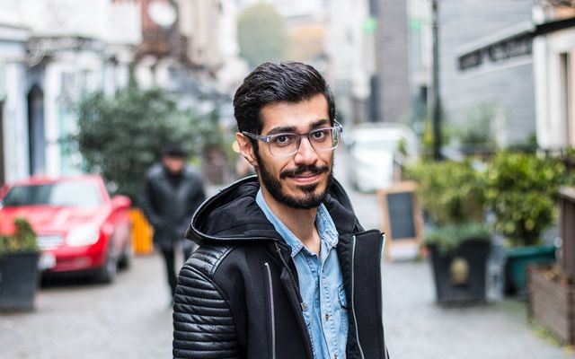 A smiling student in a black jacket on a European street