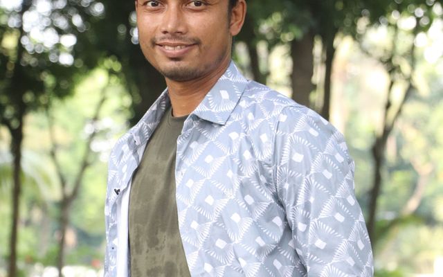 A student standing among trees in a garden