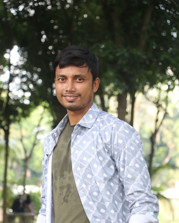 A student standing among trees in a garden