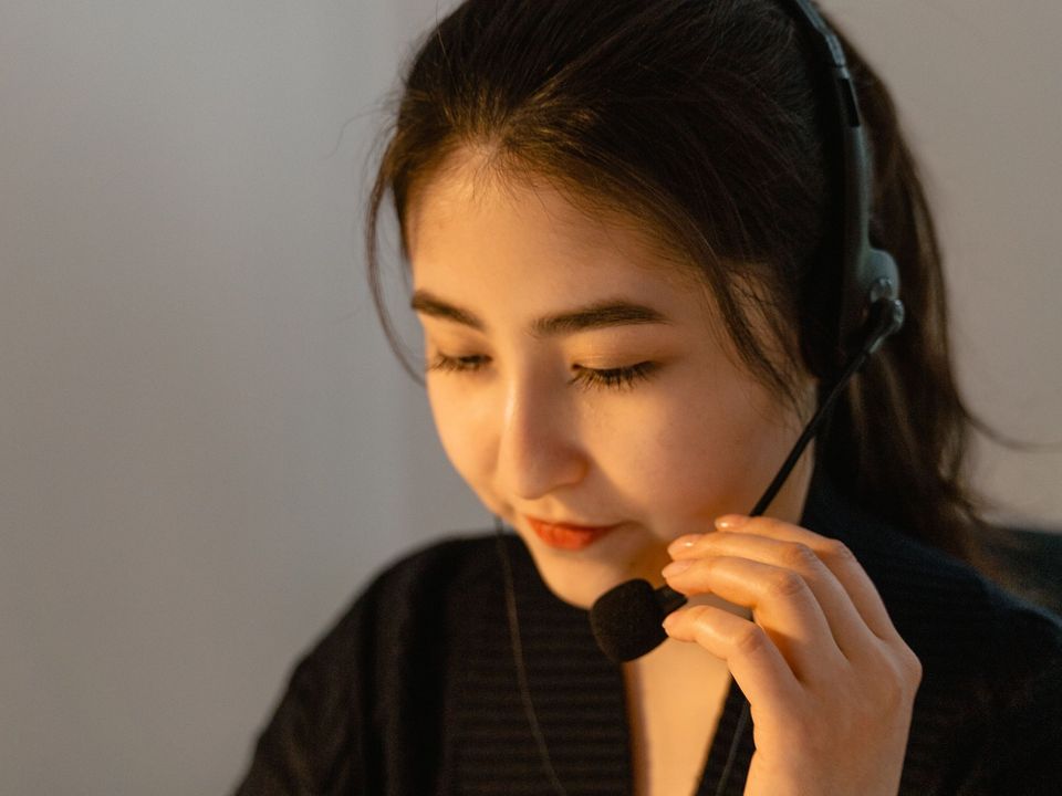 A student in a headset practising speaking at a laptop in the evening