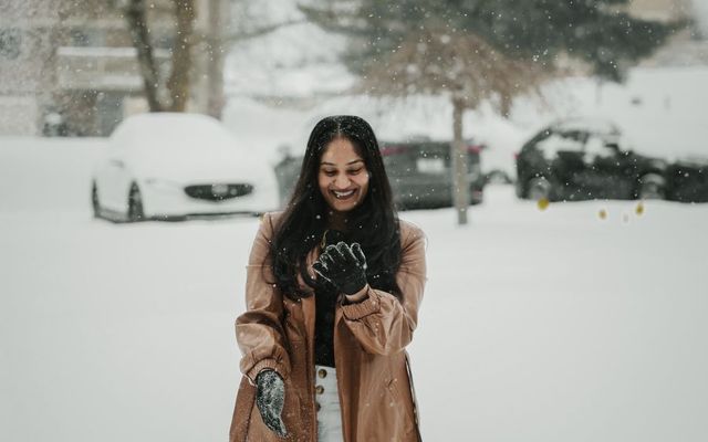 A student in a long winter coat standing in fresh snow