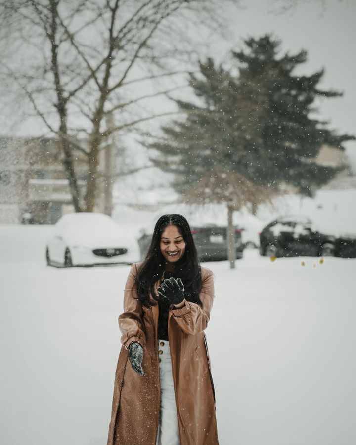 A student in a long winter coat standing in fresh snow