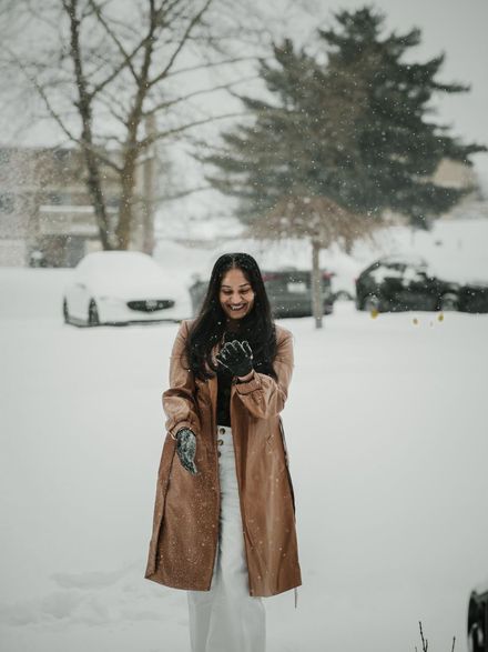 A student in a long winter coat standing in fresh snow