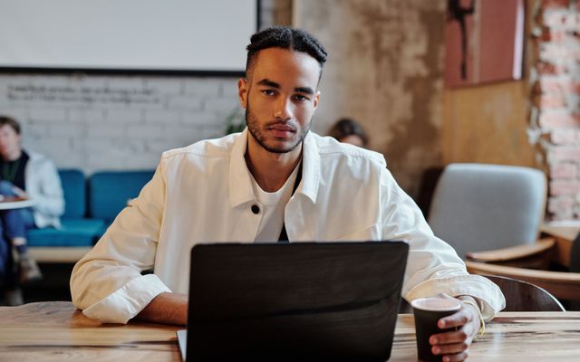 A student focused on his laptop in a cafe