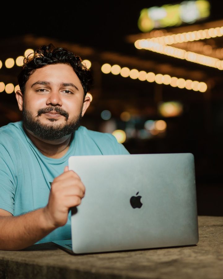 A student working on his laptop in a cafe with warm lights