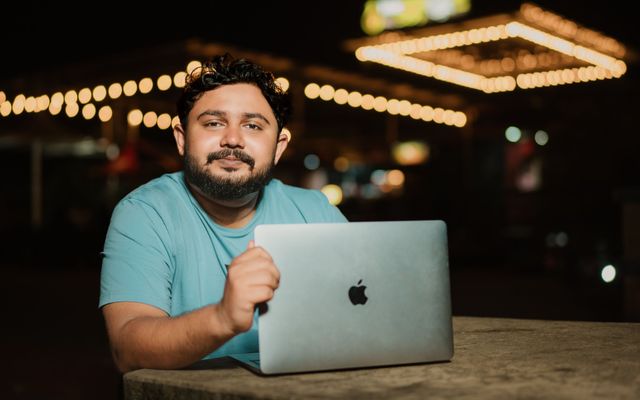 A student working on his laptop in a cafe with warm lights