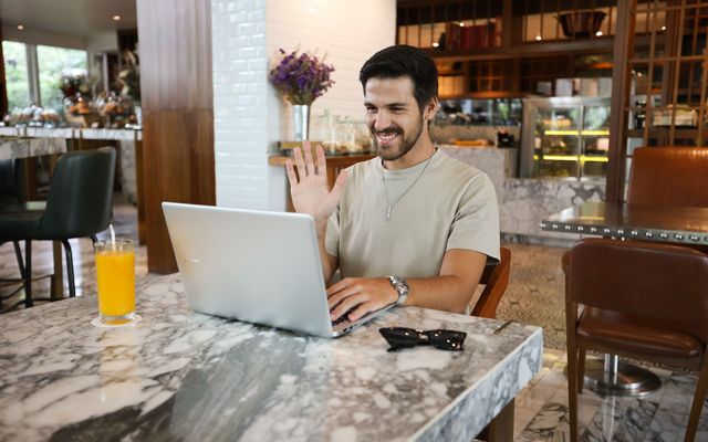 A student smiling while working on a laptop in a cafe
