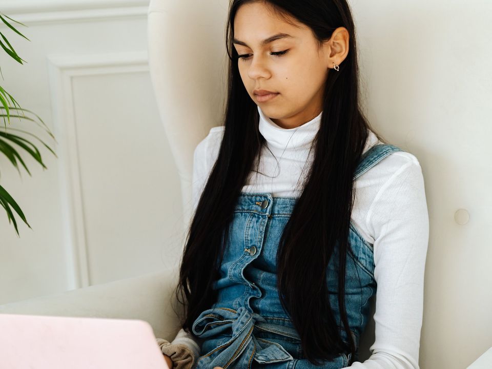 A student writing on her laptop on a sofa