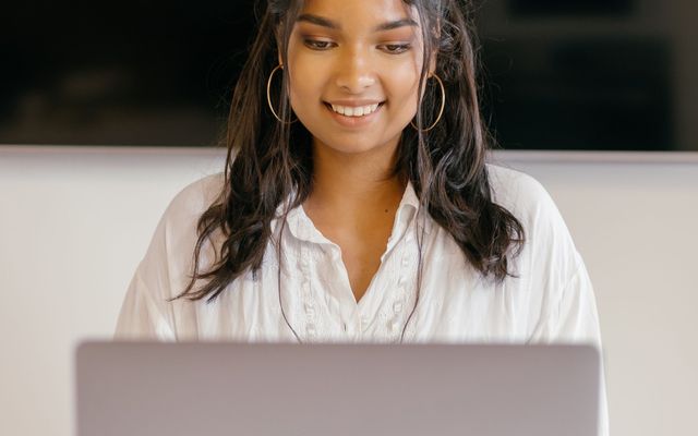 A student smiling over her laptop at a desk
